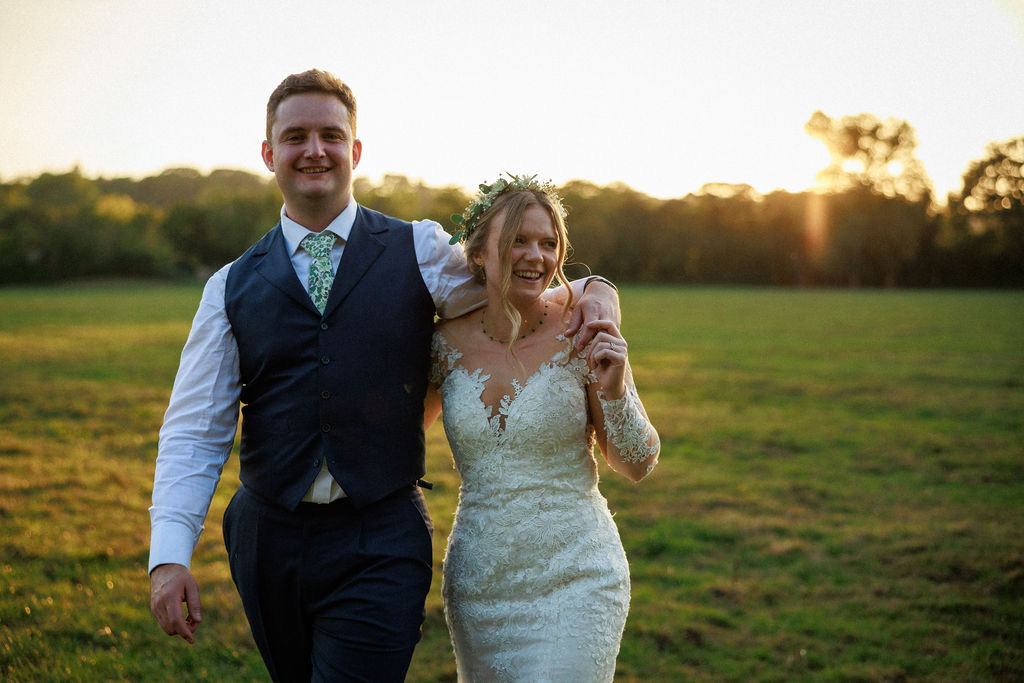 A couple walking through a field at golden hour